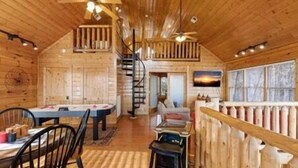 Ein Holzhütten-Innenraum mit Essbereich, einer Treppe und einem Wohnzimmer.