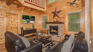 Ein gemütliches Holzhaus-Interieur mit Kamin, Ledersofas, einer Sternen-Dekoration und einem Deckenventilator.