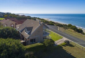 A coastal house with a balcony overlooking the beach and ocean.
