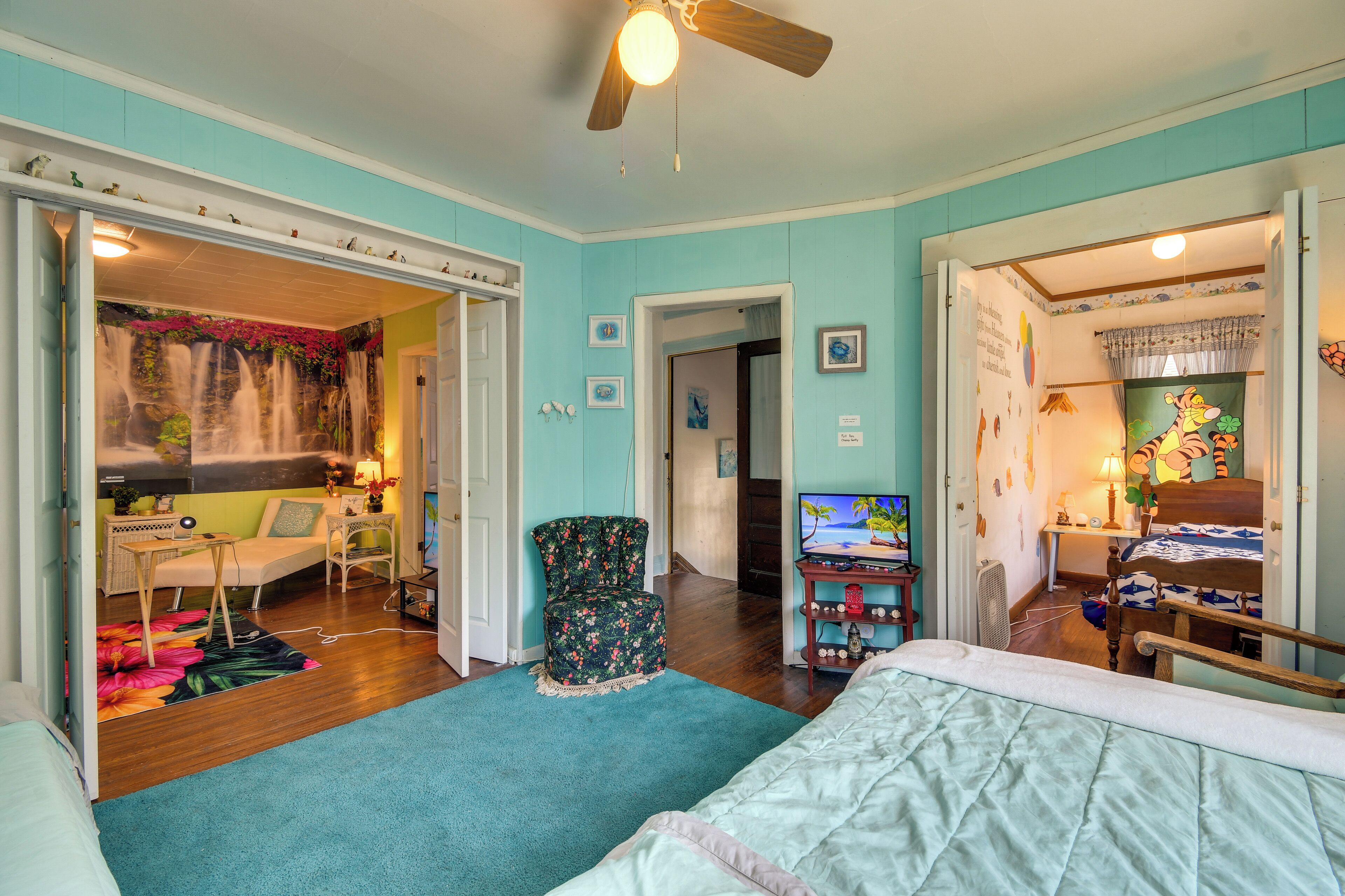 A spacious bedroom with a large bed, a desk, and a television.