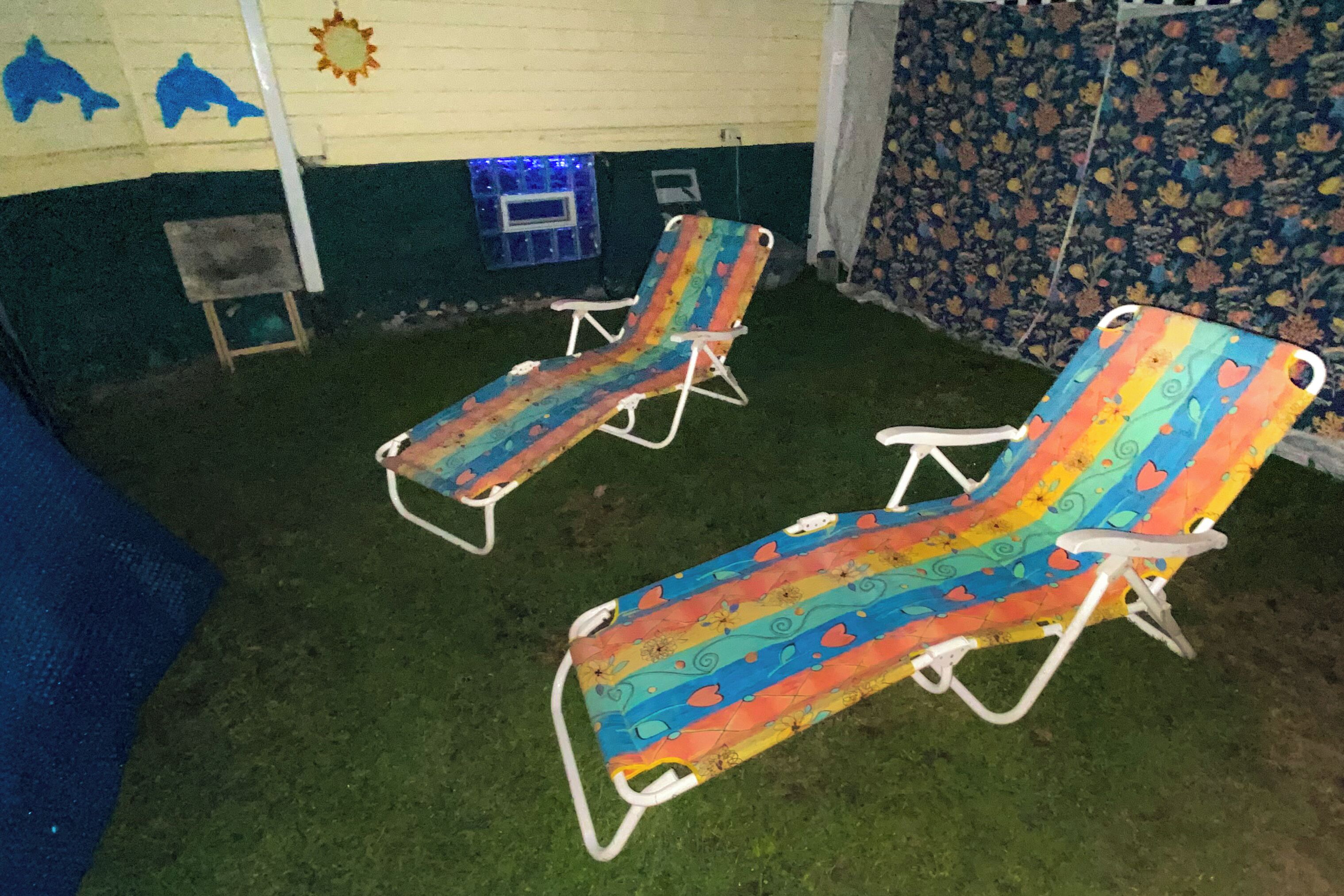 Two lounge chairs with a colorful pattern, a small table, and a wall with a sun decoration.