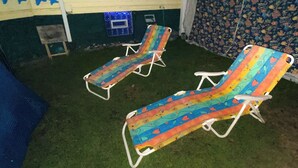 Two lounge chairs with a colorful pattern, a small table, and a wall with a sun decoration.