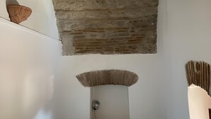 A bedroom with a stone ceiling, a bed with a blue mattress, a wall-mounted lamp, and a small shelf with a decorative item. - Casa Felice Uno - Contrada Guido (con piscina) (Sellia Marina)