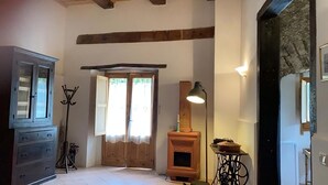 A room with a wooden cabinet, a coat rack, a wooden door, a table with a lamp, and a stone wall. - Casa Felice Uno - Contrada Guido (con piscina) (Sellia Marina)