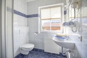 A bathroom with a toilet, a sink, and a window. - Aparthotel Pichler (Flachau)