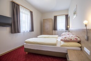A hotel room with a bed, a wooden wardrobe, a flat-screen TV, and a bedside table with a lamp. - Aparthotel Pichler (Flachau)