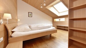 Een slaapkamer met een houten bed, dakraam en ingebouwde planken.