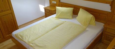 A wooden bed with a headboard, two bedside tables, and a window with curtains.