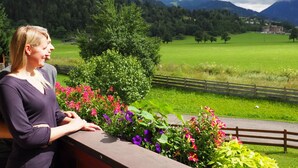A woman standing by a railing overlooking a green field with a mountain in the background. - Reiterhof (Sankt Johann im Pongau)