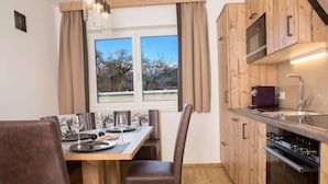 A modern kitchen with wooden cabinets, a built-in oven, and a window with a view of trees. - Reiterhof (Sankt Johann im Pongau)