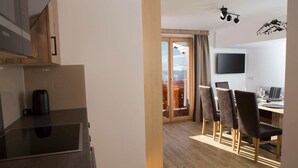 A modern kitchen with a kettle, a dining area with a table and chairs, and a TV mounted on the wall. - Reiterhof (Sankt Johann im Pongau)