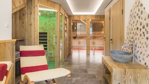 A modern spa area with wooden walls, a stone sink, and a relaxation chair. - Erbhof Hinterrain (Leogang)