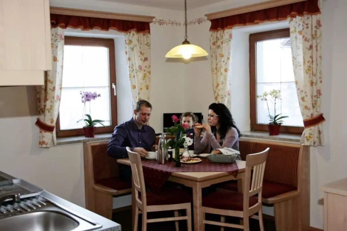 A dining area with a table, chairs, and a hanging light fixture.