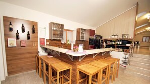 A modern kitchen with wooden bar stools, wine bottles, and a built-in wine fridge.