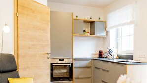 A modern kitchen with built-in appliances, a dining area with a table and chairs, and a cozy seating area with a sofa and a lamp.