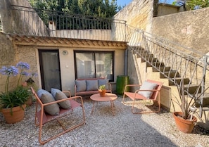 A patio with outdoor seating, a staircase, and a view of the surrounding area. - La Petite Cour: Stone and Charm in the Heart of Uzès (Uzès)
