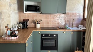 Een keuken met een magnetron, oven en een betegelde spatwand.