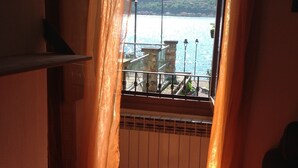 A room with a view of a lake and mountains through sheer curtains.