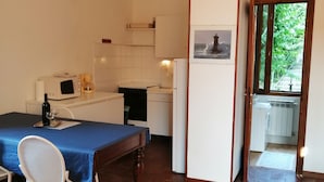 A compact kitchen with white cabinets, a microwave, and a coffee maker. A dining table with chairs is positioned in the foreground.