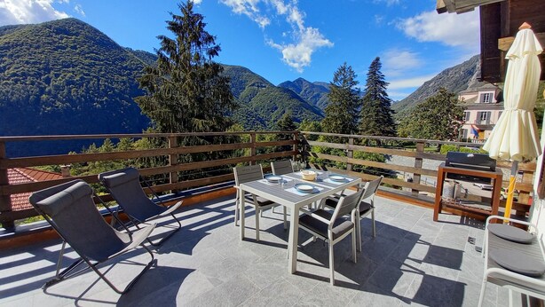 Une terrasse avec une table et des chaises, offrant une vue sur un paysage montagneux.