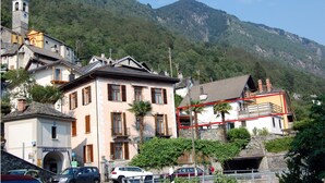 Un bâtiment doté d’un balcon, d’une tour en pierre et ayant une chaîne de montagnes en arrière-plan.