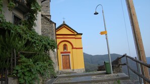 Une église jaune avec une porte en bois, entourée d’escaliers en pierre et de verdure.