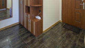 Una habitación con un armario de madera, una puerta y suelo de baldosas.
