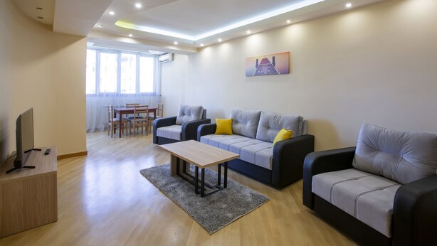 Una sala de estar moderna con un sofá, una mesa de centro y un televisor sobre un mueble.