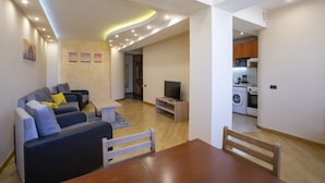 Una sala moderna con un sofá, una mesa de comedor de madera y un televisor.