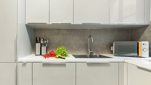 Una cocina moderna con armarios blancos, un lavamanos de acero inoxidable y un microondas.