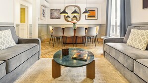 Una sala de estar moderna con un juego de sofá, una mesa de centro con un libro y un comedor con sillas y una mesa.