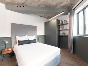 A modern bedroom with a large bed, bedside tables, a wardrobe, and a window with curtains.