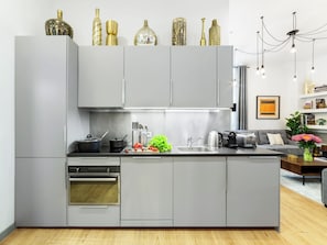 Une cuisine moderne avec des meubles gris, un four encastré et un plan de travail sur lequel sont disposés divers ustensiles de cuisine.