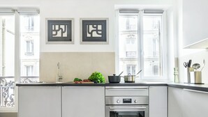 Uma cozinha moderna com forno embutido, pia e janela com vista para prédios.