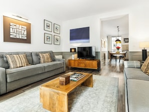 A modern living room with a grey sofa, wooden coffee table, and a flat-screen TV.