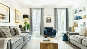 Uma sala de estar moderna com um sofá, poltrona, mesa de centro e estante.