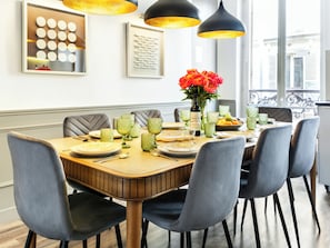 A dining table set with plates, glasses, and a vase of flowers, surrounded by chairs.
