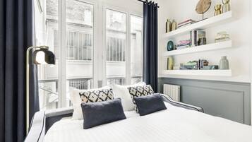 Una camera da letto moderna con un letto grande, una lampada da terra e vista sugli edifici.