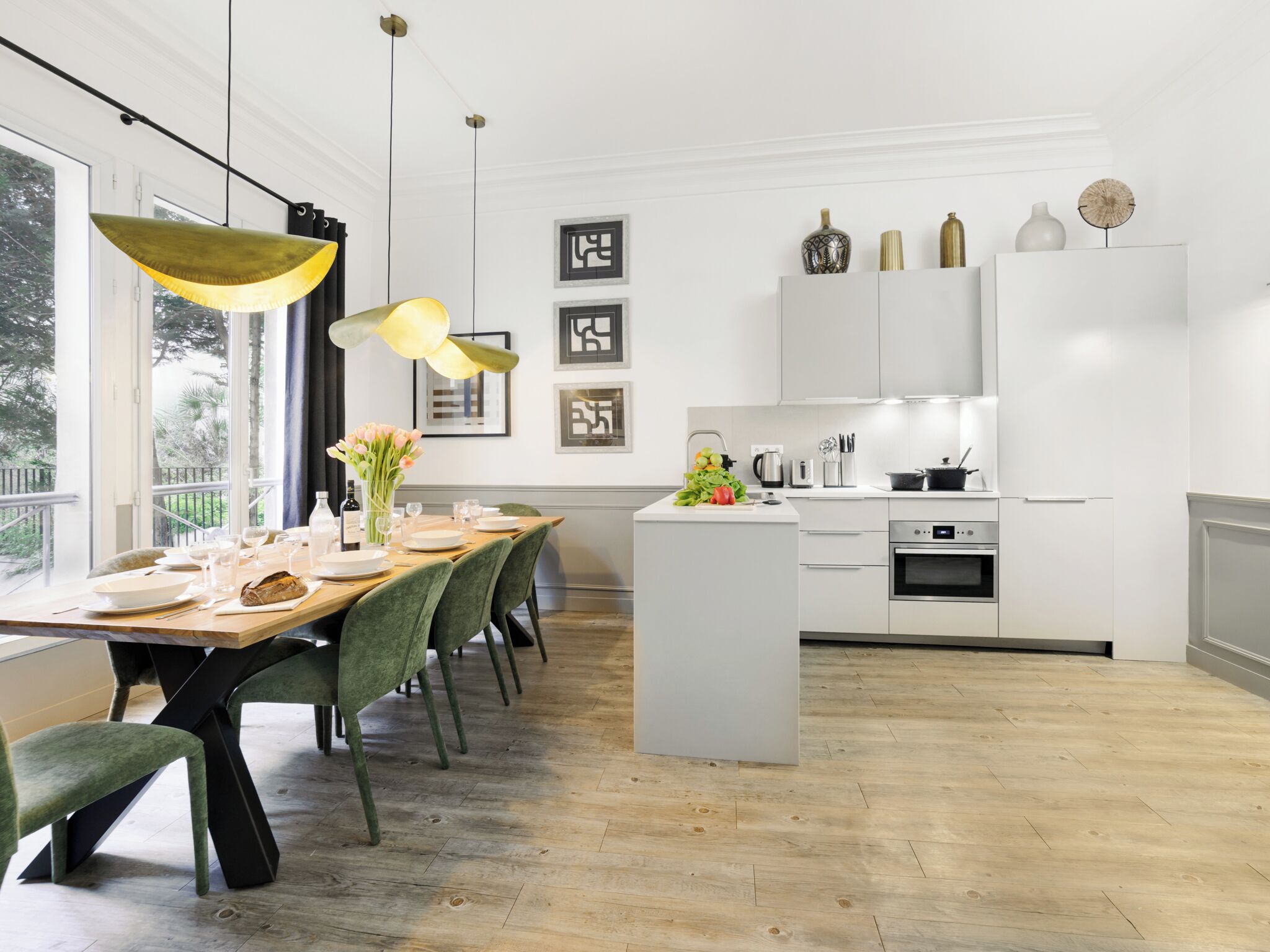 Une cuisine moderne avec des meubles blancs, un îlot central et des luminaires suspendus.