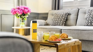A cozy living room with a sofa, a coffee table with breakfast items, and a vase of flowers. - LivinParis | Luxury AC 3 Bedrooms Le Louvre - Eiffel View (Paris)