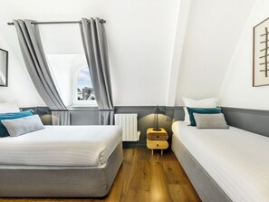 A hotel room with a bed, a bedside table with a lamp, and a window with curtains.