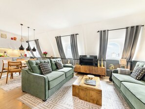 A modern living room with a green sofa, a wooden coffee table, and a TV. - LivinParis | Luxury AC 2 Bedrooms Le Louvre - Sacré Cœur View (Paris)