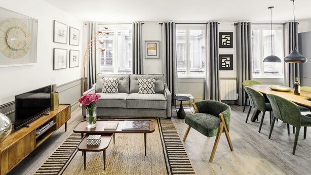 A modern living room with a sofa, coffee table, and dining area.