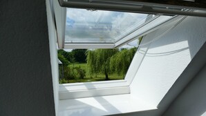 A skylight with a view of a green landscape and trees. - Small vacation apartment at Wulfkamp (Velen)