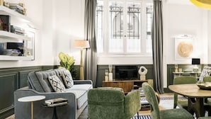 A modern living room with a grey sofa, green armchairs, a coffee table, and a TV. - LivinParis | Luxury AC 3 Bedrooms République I (Paris)