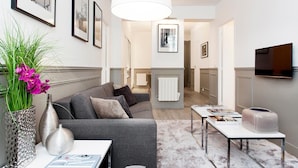Ein modernes Wohnzimmer mit einem grauen Sofa, einem weißen Tisch und einer großen Pendelleuchte.