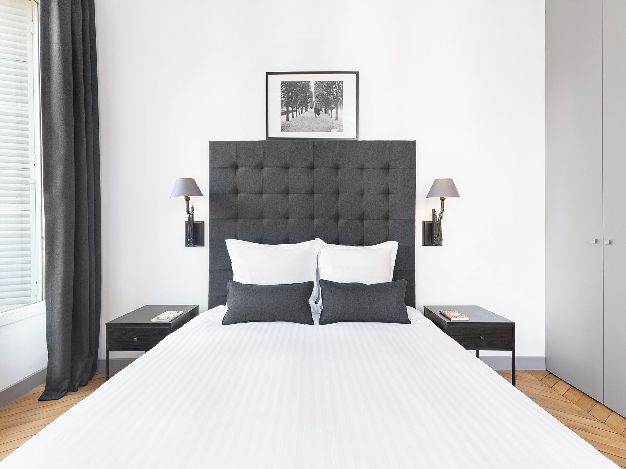 Un dormitorio moderno con una cama grande, dos mesitas de noche, un cabecero y un cuadro enmarcado en la pared.