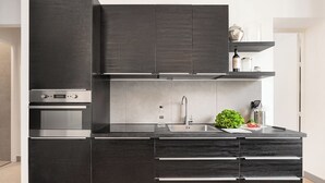 Una cocina moderna con armarios oscuros, electrodomésticos de acero inoxidable y un diseño minimalista.