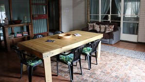 Un comedor con una mesa y sillas de madera, una estantería y un sofá con cojines estampados.