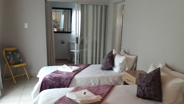 Habitación de hotel con dos camas, techo de madera y vistas a un balcón.